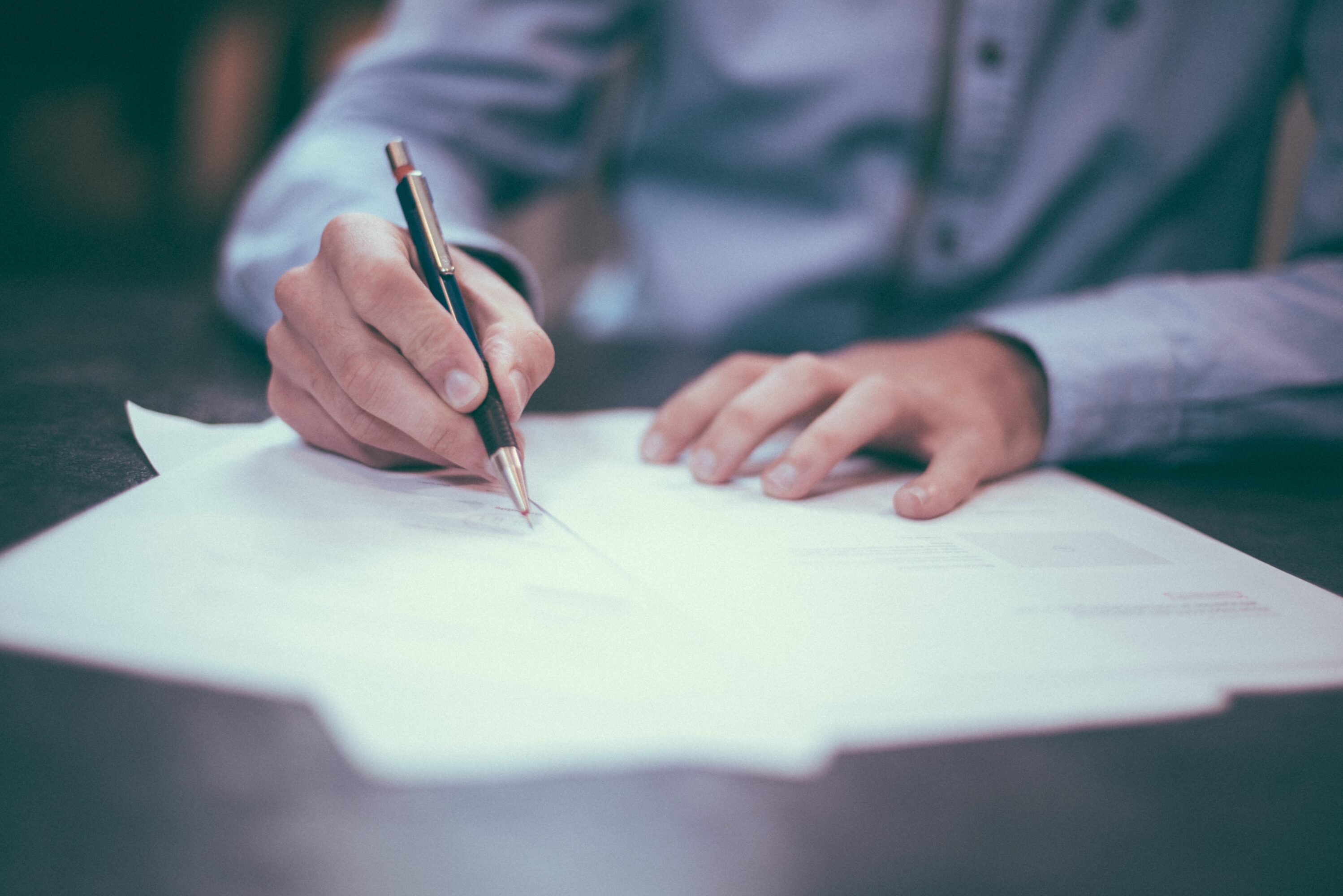 Person writing on paper with a pen.