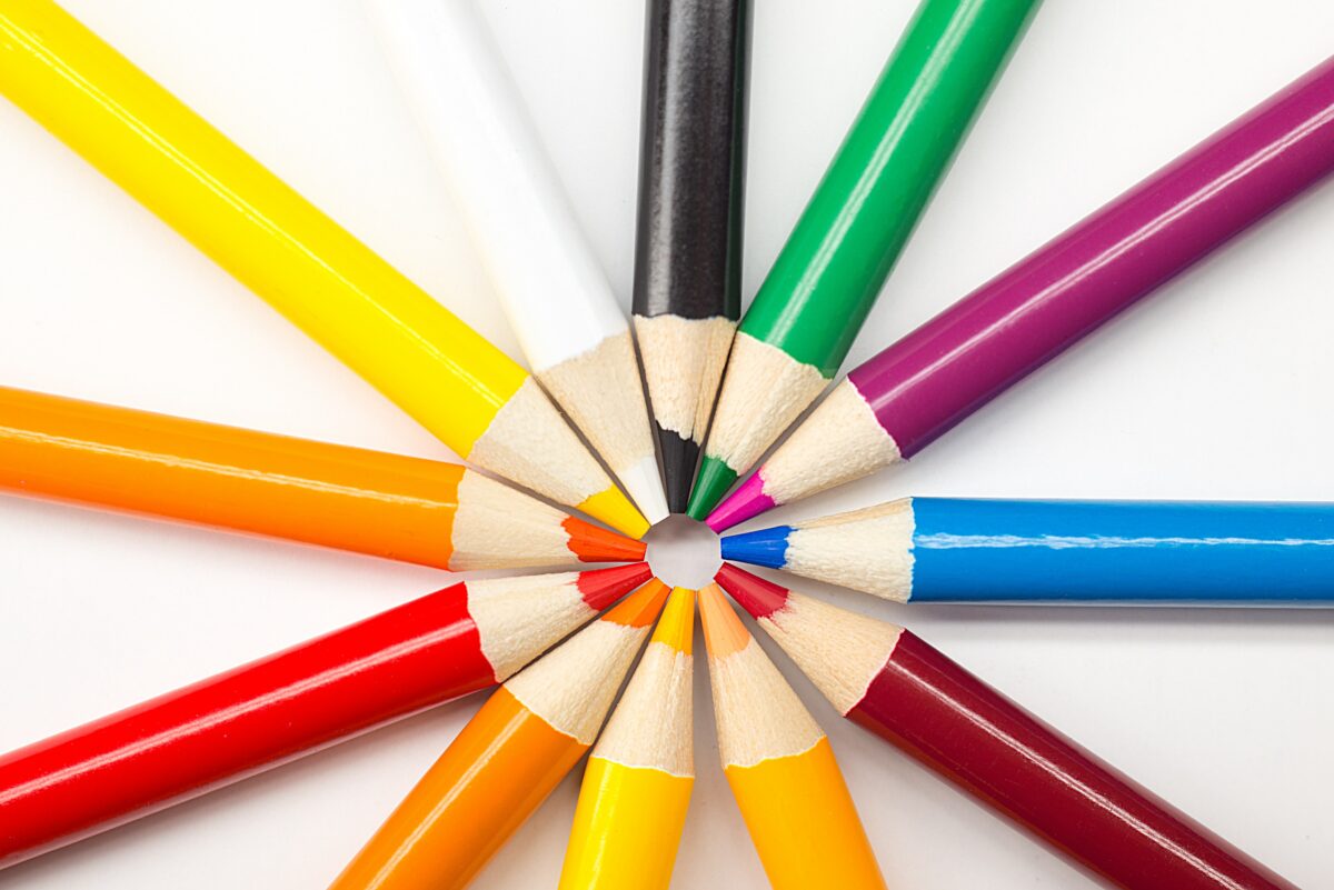 A collection of rainbow-colored pencils arranged in a circle with their tips pointed in.